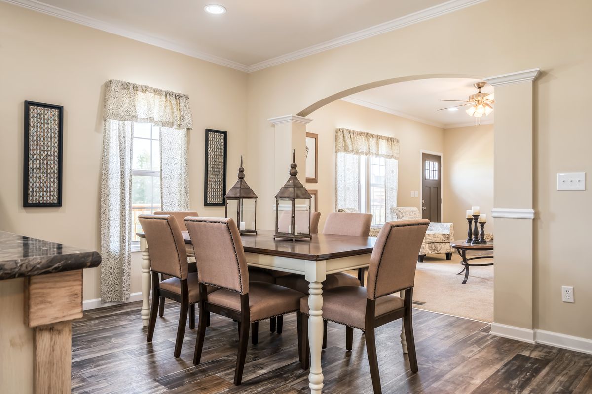 A dining room with hardwood floors and an archway.