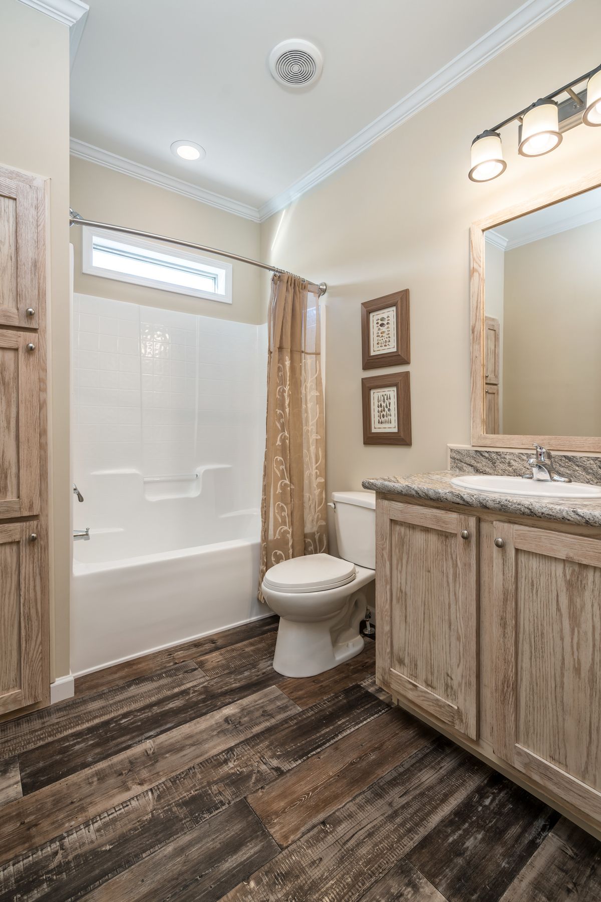 A bathroom with wood floors and wooden cabinets.