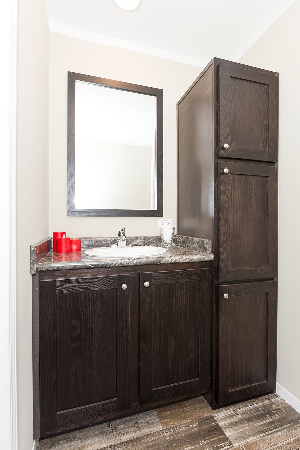 null A bathroom with dark wood cabinets and a mirror.