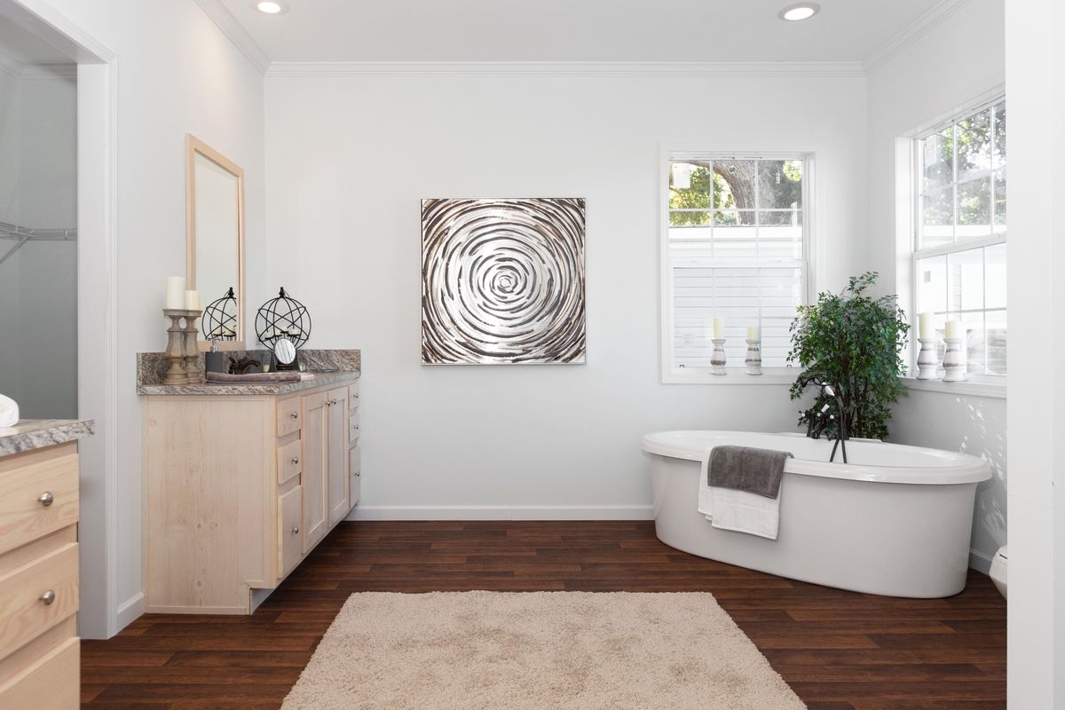 A white bathroom with hardwood floors and a bathtub.