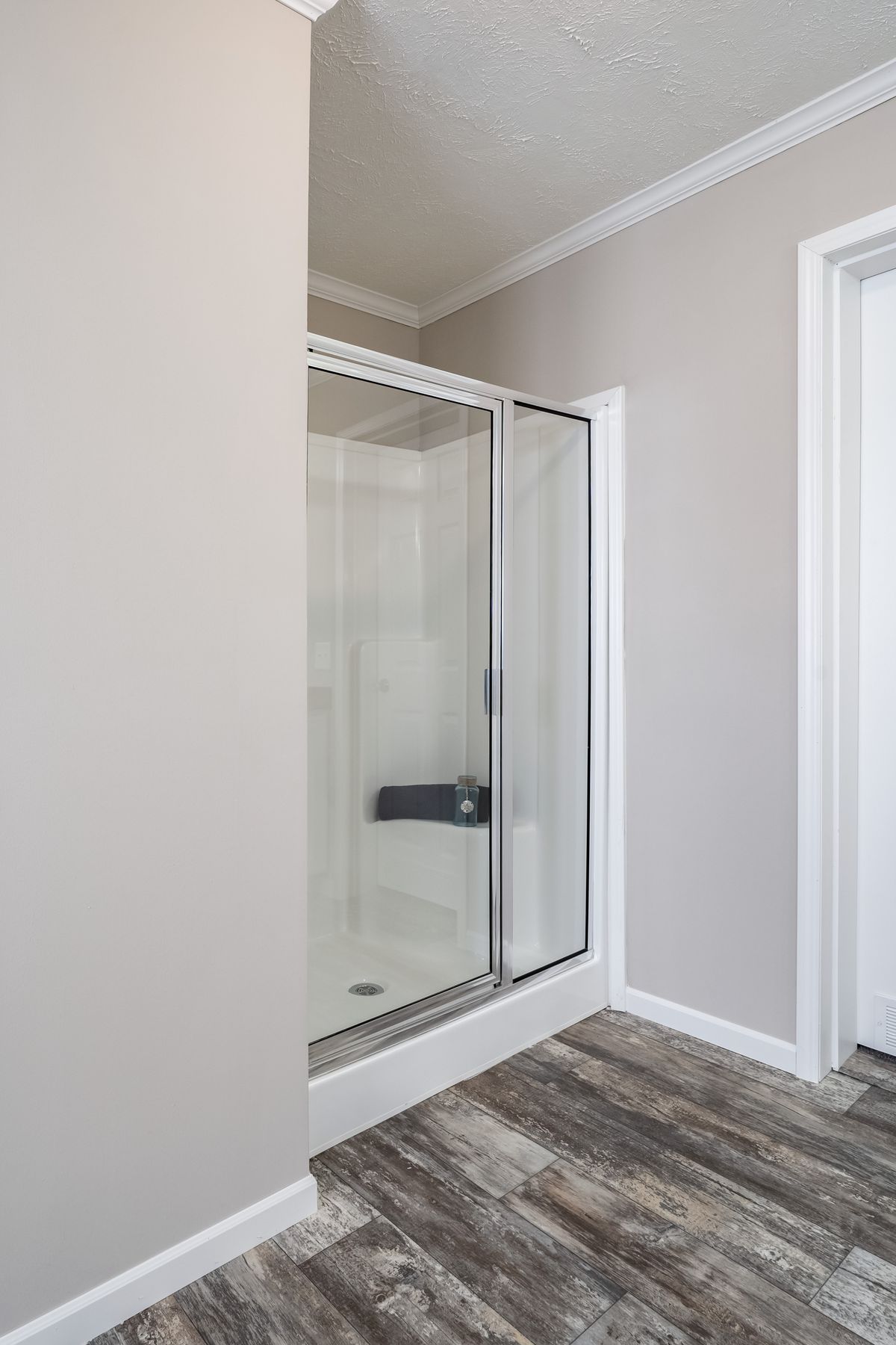 A bathroom with a shower stall and wood floors.