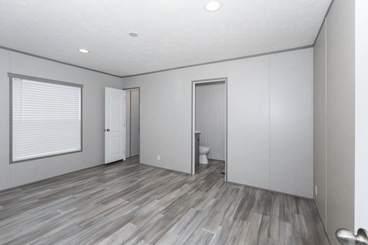 a44dbfd7-2c6a-49f2-a58a-23dc3f50a38b An empty room with wood floors and white walls.