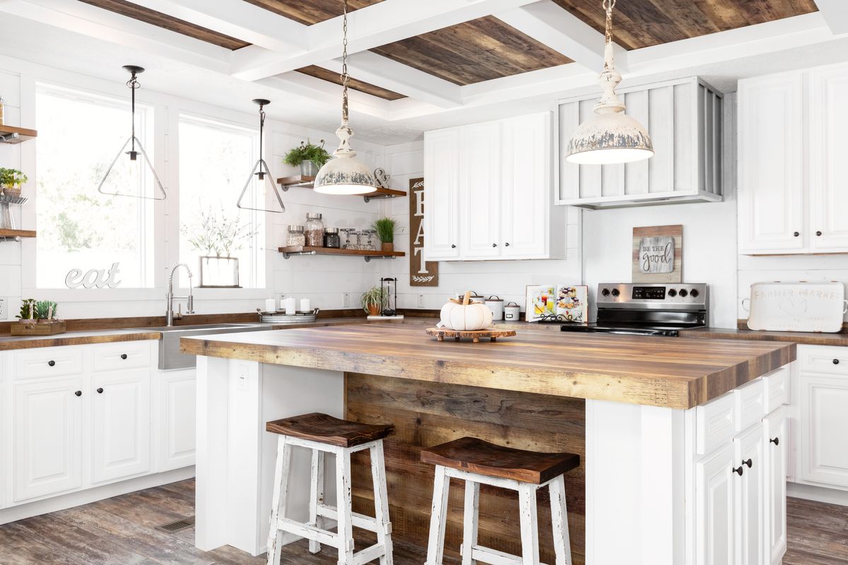 A white kitchen with wood ceilings and stools.