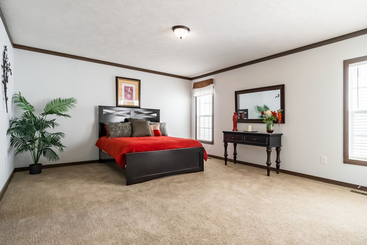 A bedroom with a bed, dresser and mirror.