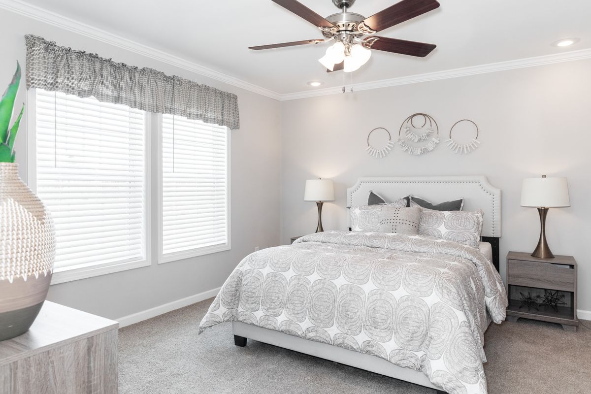 a90c899a-a9c4-4ba2-b89b-4c3ba387eff0 A bedroom with a bed, dresser, and ceiling fan.