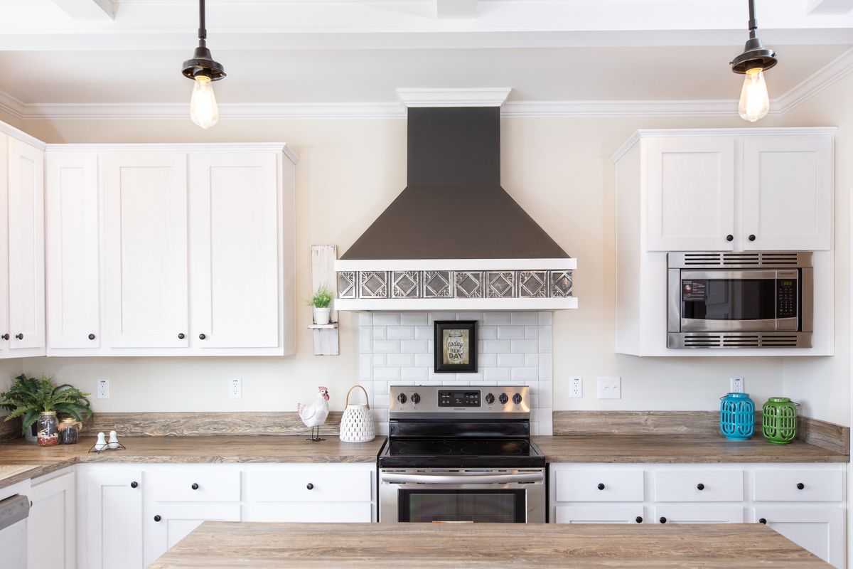 aa49e7c5-b77d-4146-aed4-d181724e4f80 A kitchen with white cabinets and a wood stove.