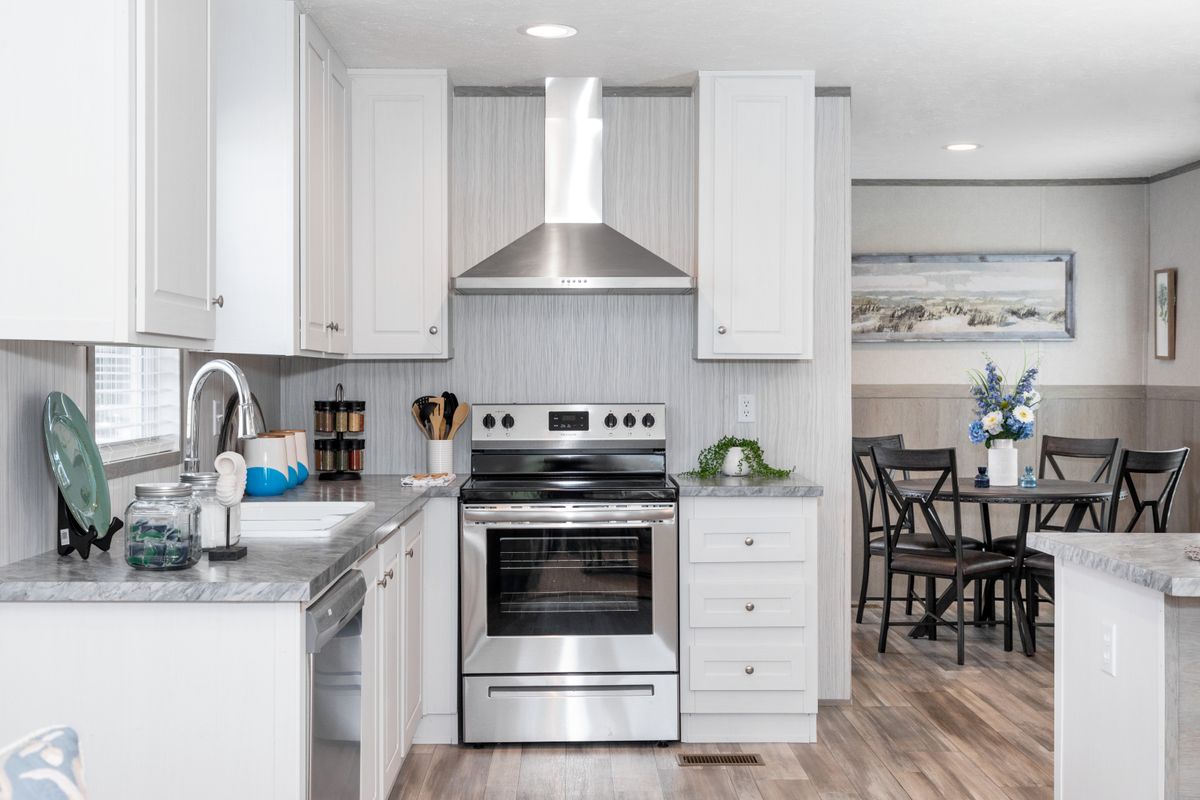ab826b3f-4303-4af0-a134-0cd8235baa4b A white kitchen with stainless steel appliances and hardwood floors.