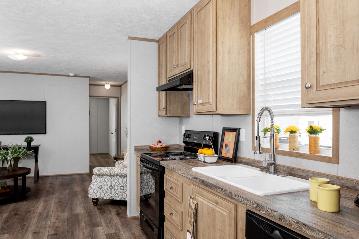 A kitchen in a mobile home with wood cabinets and a tv.