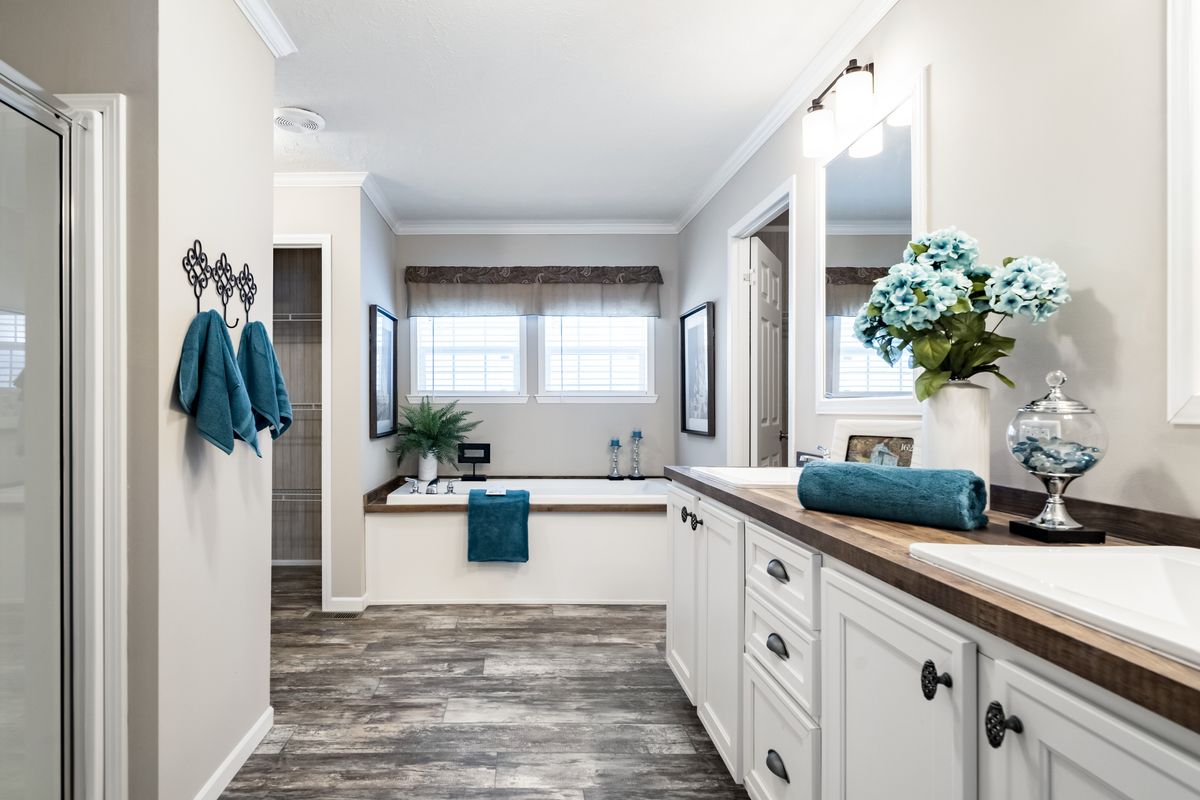 A white bathroom with blue towels and wood floors.