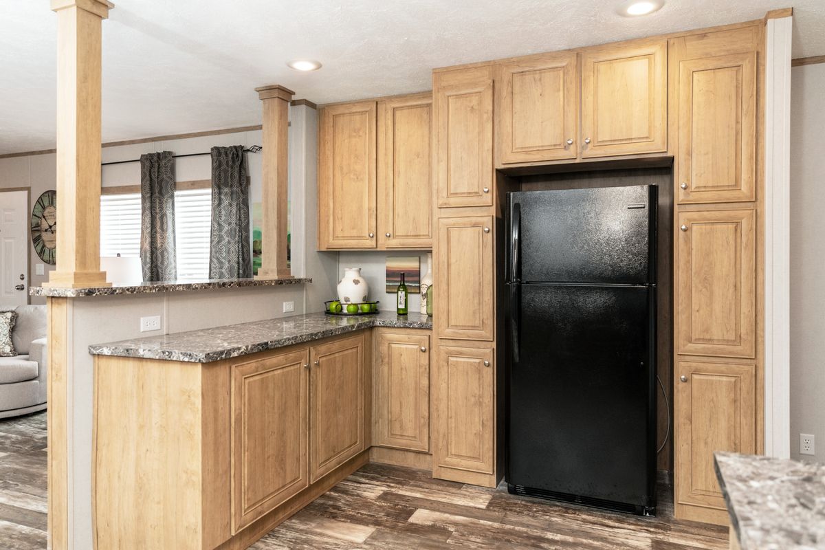 A kitchen in a mobile home with wood cabinets and granite counter tops.