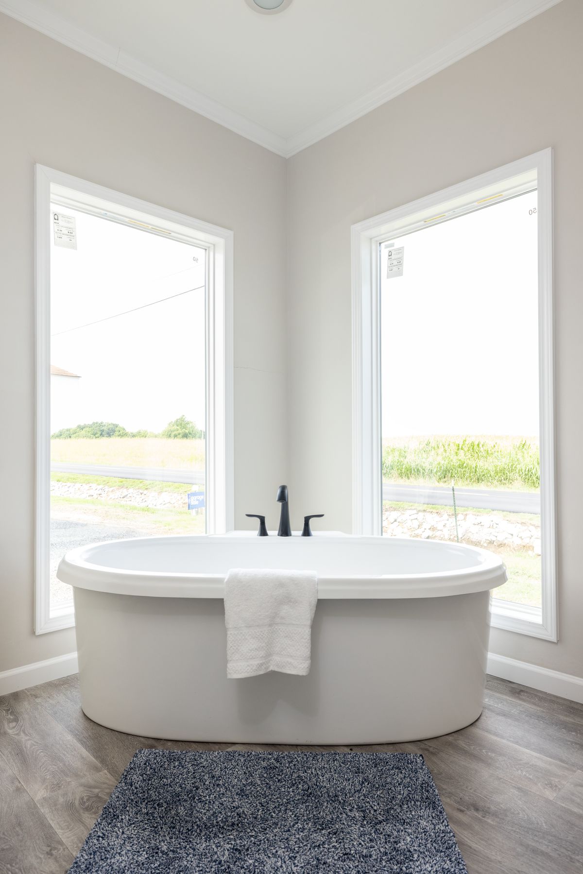 bb85ae98-a4a8-44b9-b0d6-597cff6ac237 A white bathtub in a bathroom with large windows.