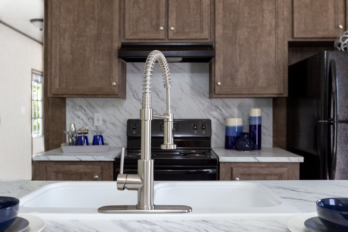 bdb3ca6b-3e5c-4d50-9a7b-d12a4958714b A kitchen in a mobile home with marble counter tops and stainless steel appliances.