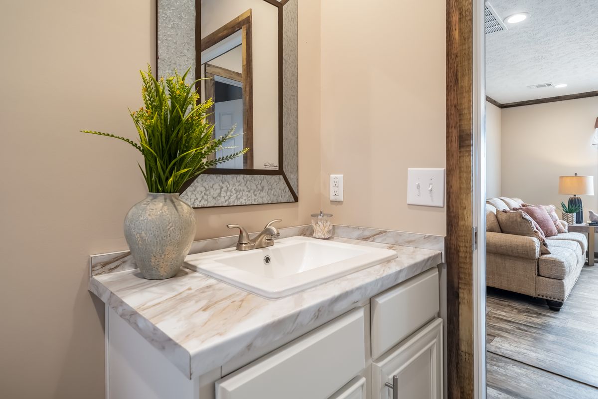 A bathroom in a mobile home with a sink and mirror.