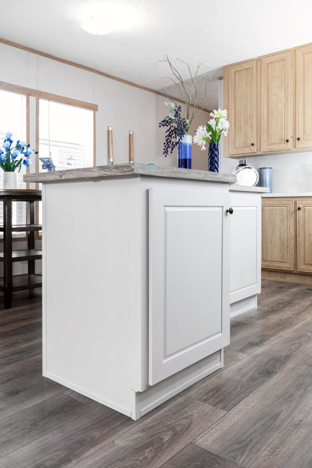 bffde9e5-420e-47ec-a4a0-690e60990926 A kitchen with wood floors and white cabinets.