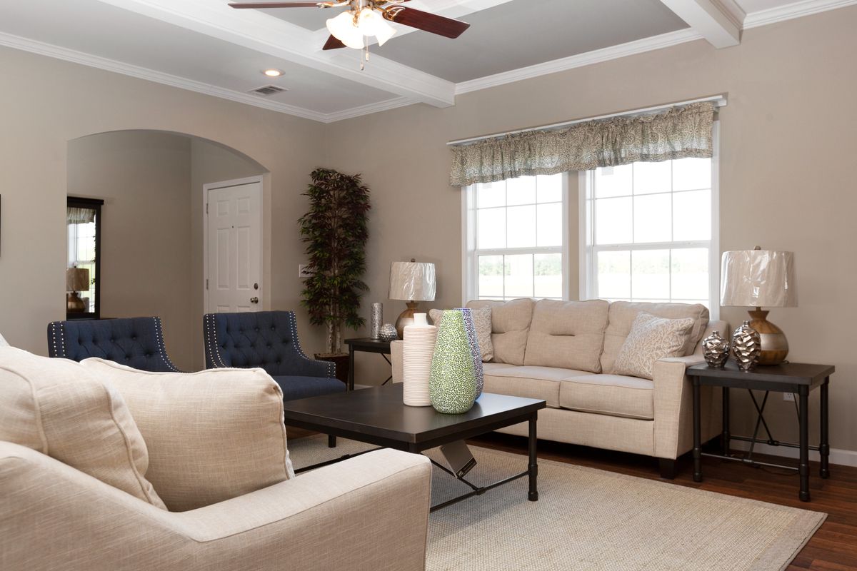 A living room with beige furniture and a ceiling fan.