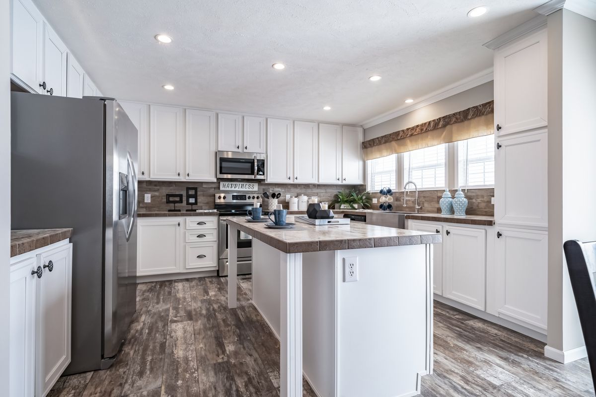 A kitchen with white cabinets and hardwood floors.