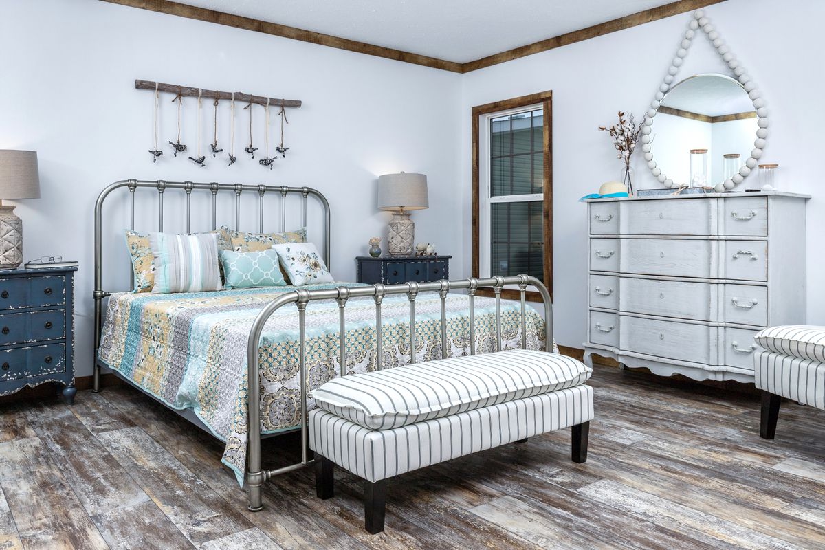 A bedroom with wood floors and a metal bed.