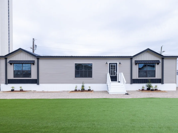 A mobile home with grass in front of it.