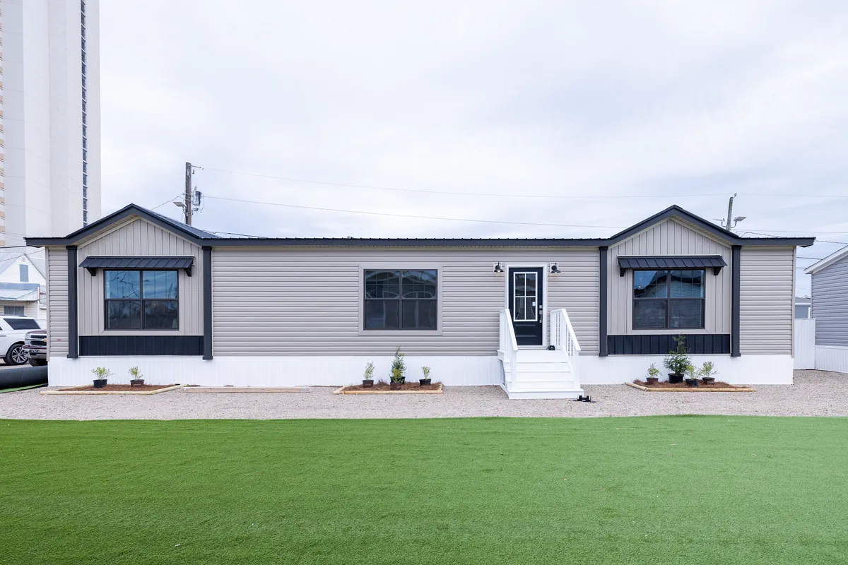 ca943960-04b8-436c-bdda-8978c3995179 A mobile home with grass in front of it.