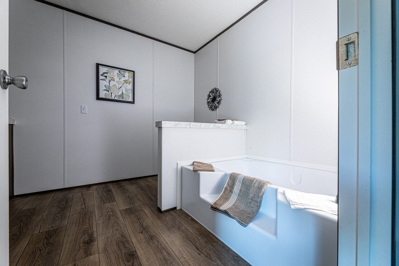 A bathroom with a bathtub and white walls.