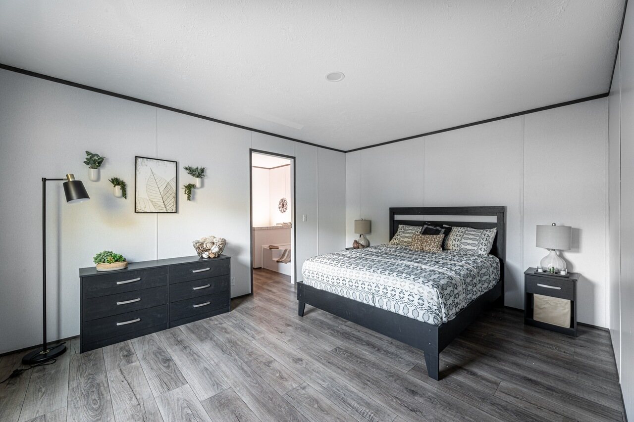 A bedroom with a bed, dresser, and dresser.