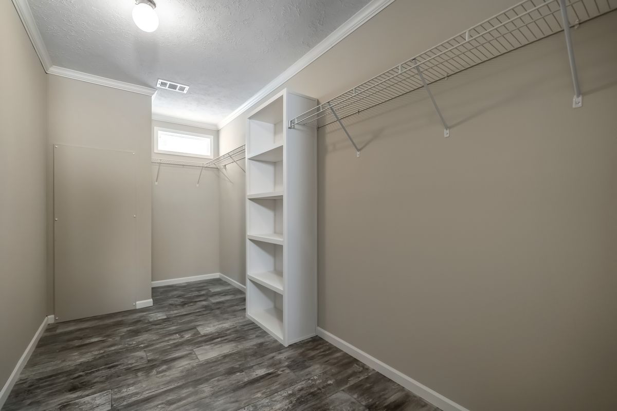 cb05e7fc-36b5-4eb6-bb92-27be1e7985e5 A walk in closet with shelves and wood floors.
