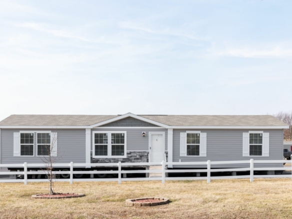 A gray mobile home with a white fence.