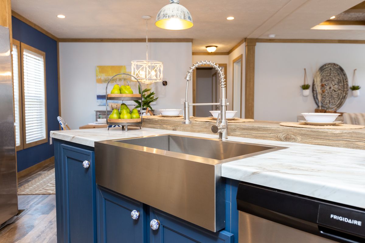 A kitchen with blue cabinets and a stainless steel sink.