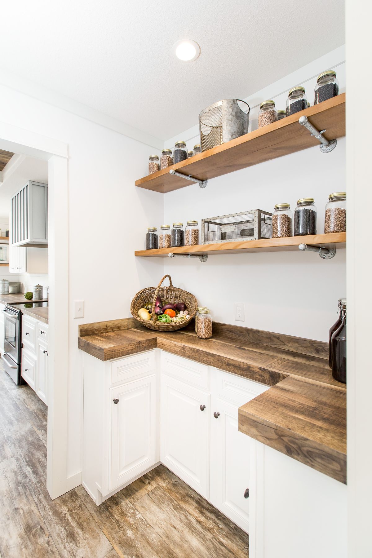A kitchen with white cabinets and wooden shelves.