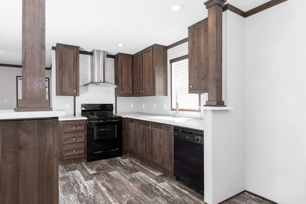A kitchen in a mobile home with wood cabinets.