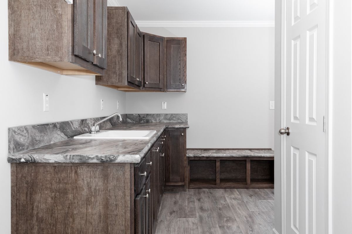 d118db37-9341-4087-929b-c99c8b76e453 A laundry room with wood cabinets and granite counter tops.