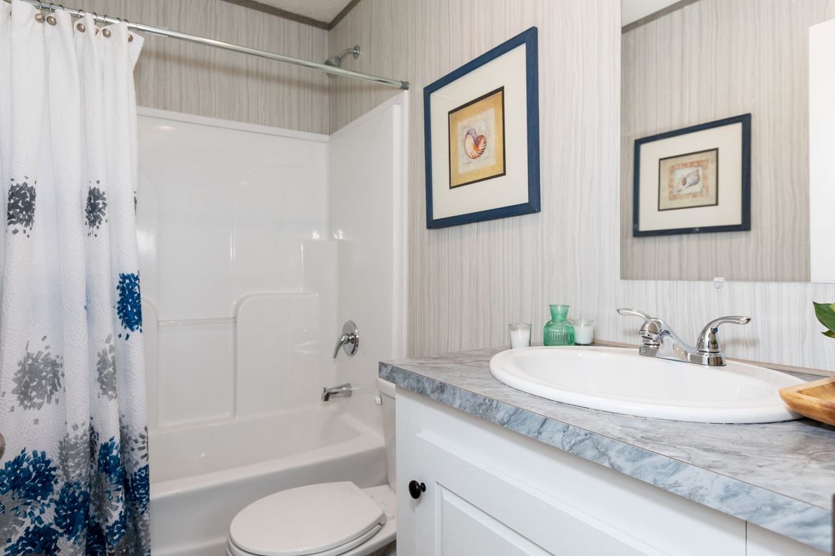 d47d6b17-c0f2-4f3c-a6f0-241306ef1691 A bathroom with a blue and white shower curtain.