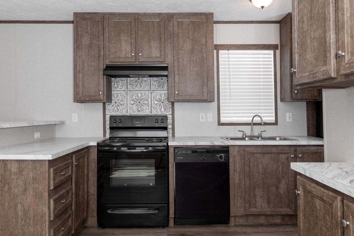 d4ac1676-344e-49bb-91ff-80b9db81d864 A kitchen in a mobile home with wood cabinets and a stove.