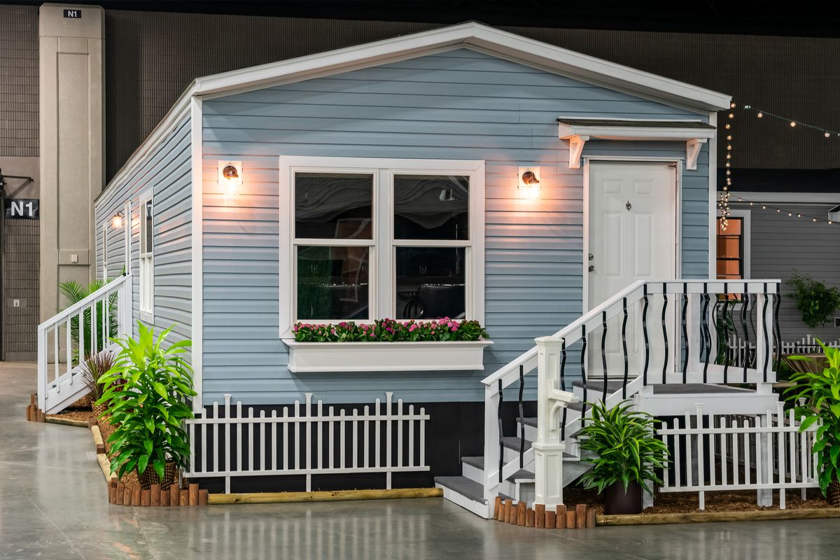 d4f4c260-1ba4-4801-92ec-5f94c9d4ae7d A blue mobile home is on display at a show.