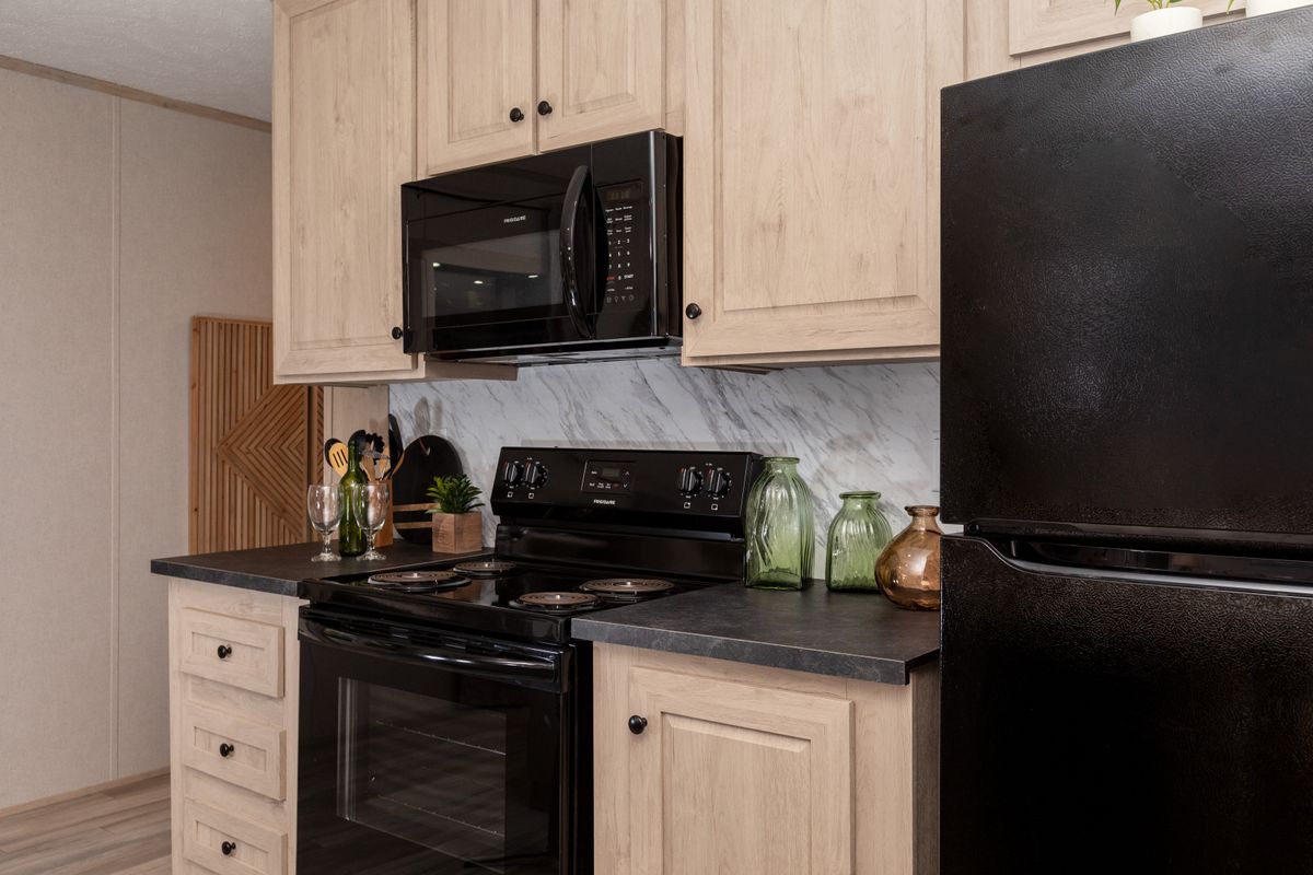 d732c8db-1f62-459a-85e7-23dbadb93100 A kitchen in a mobile home with black appliances.