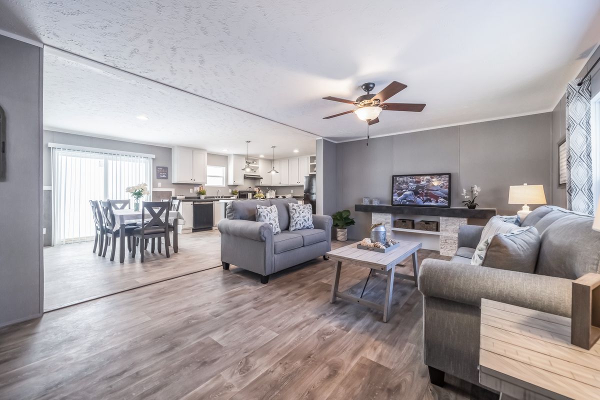 A living room with gray furniture and a ceiling fan.