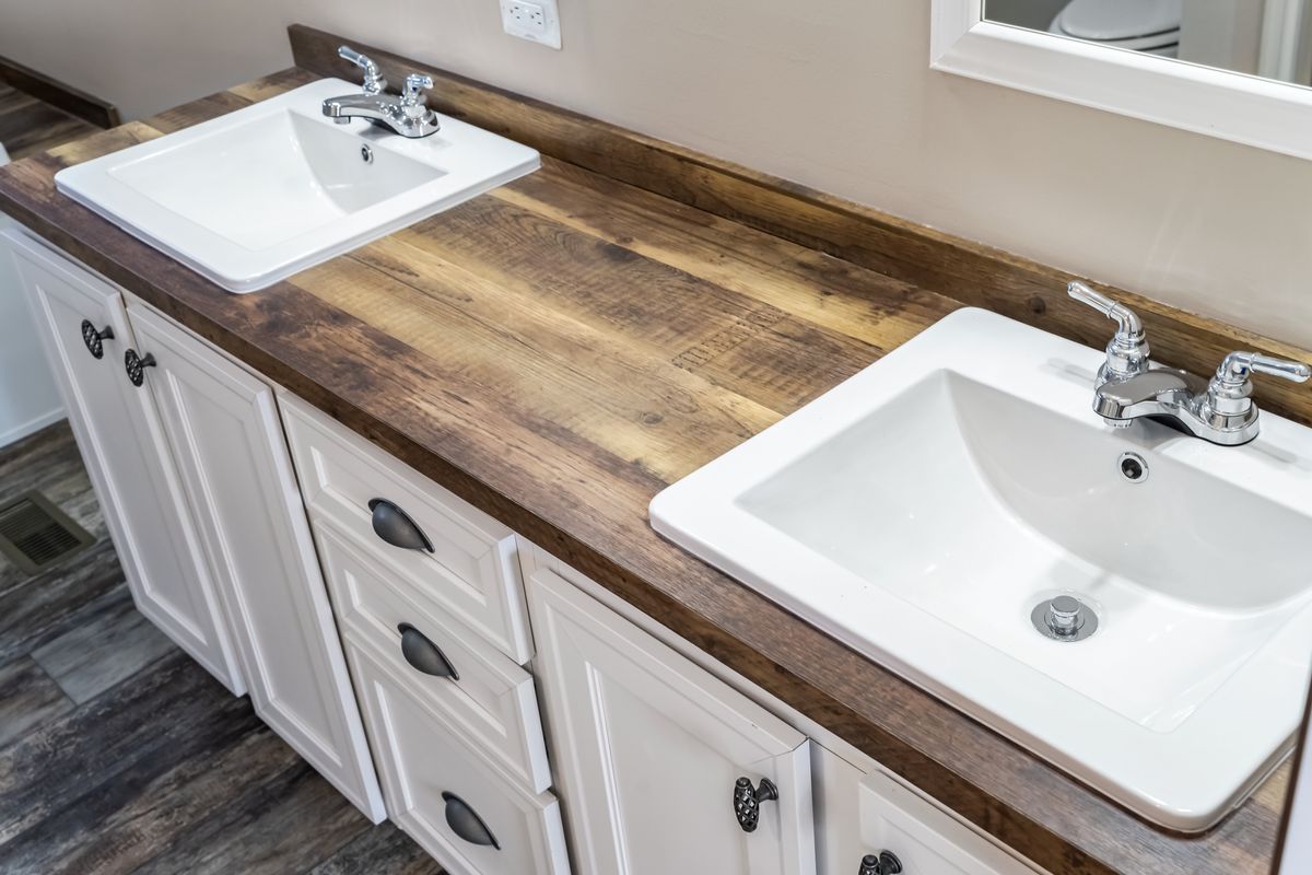 A bathroom with two sinks and a wooden counter top.