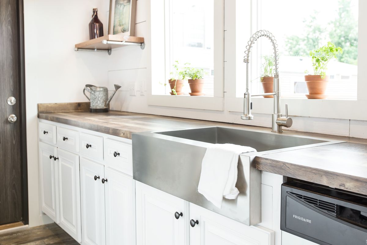 A kitchen with white cabinets and a stainless steel sink.