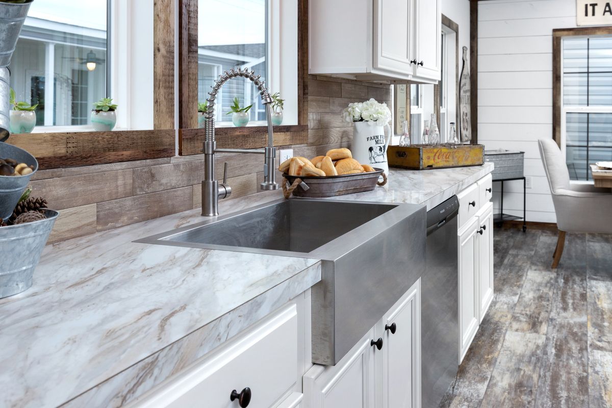A kitchen with white cabinets and wood floors.