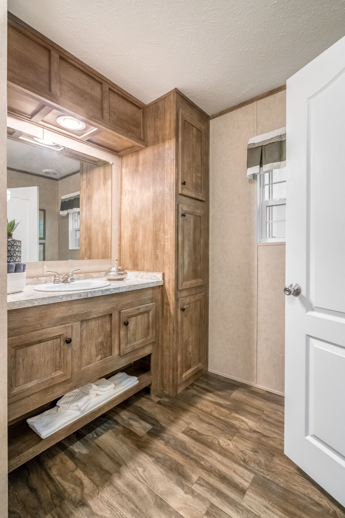 A bathroom in a mobile home with wood cabinets.