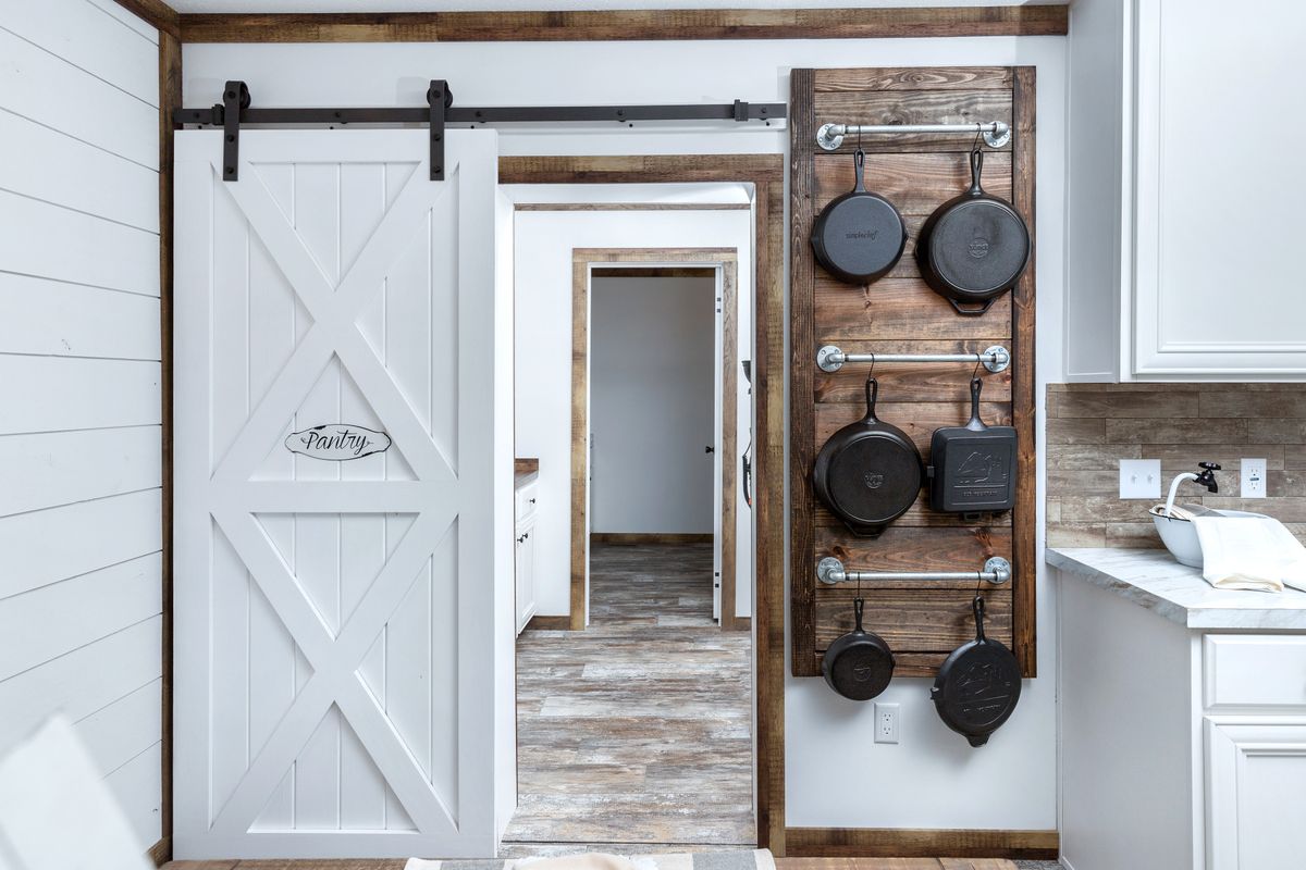A kitchen with a wooden door and pans hanging on it.