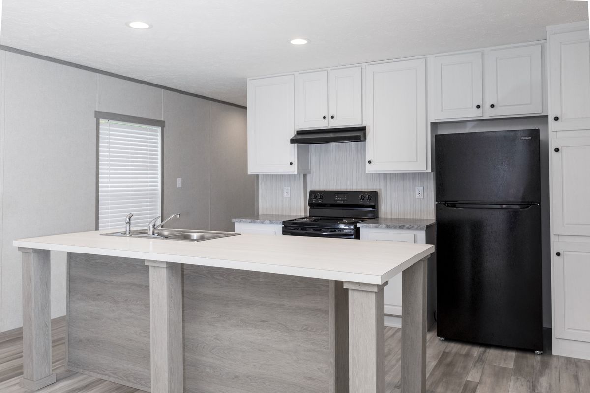e4ba498f-2327-4358-bb61-6f449a2a0c10 A white kitchen with black appliances and wood floors.