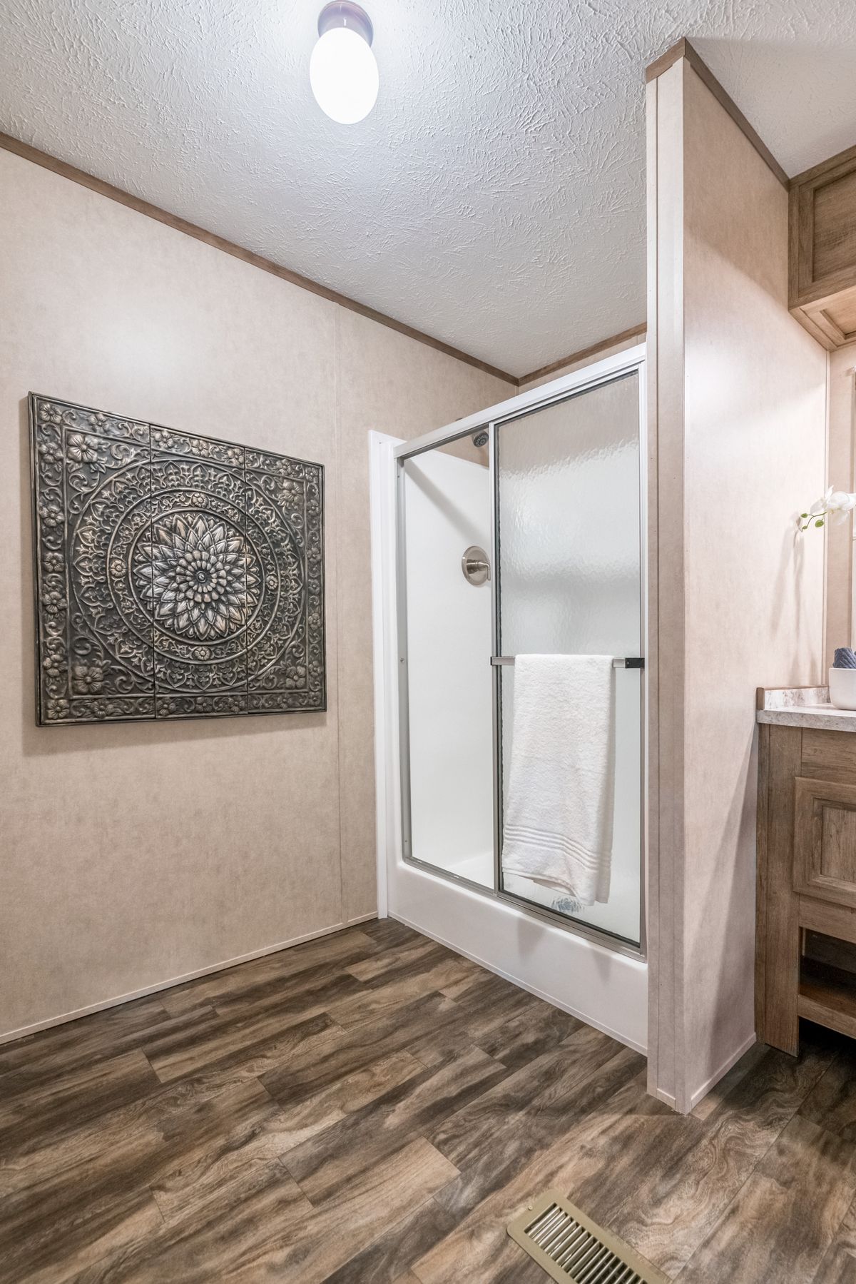 A bathroom in a mobile home with wood floors and a shower.