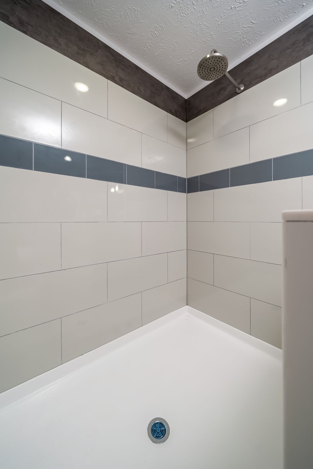 e8f8bca2-5b4e-4742-9a4d-8c312e5d06b4 A white tiled shower with a blue tiled floor.