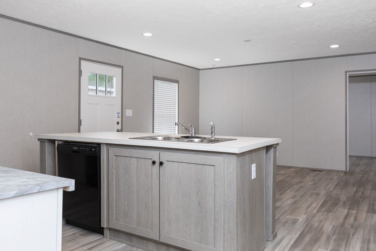ea219ca3-329e-41ee-8de3-f157a9fc8f39 A kitchen in a mobile home with wood floors.