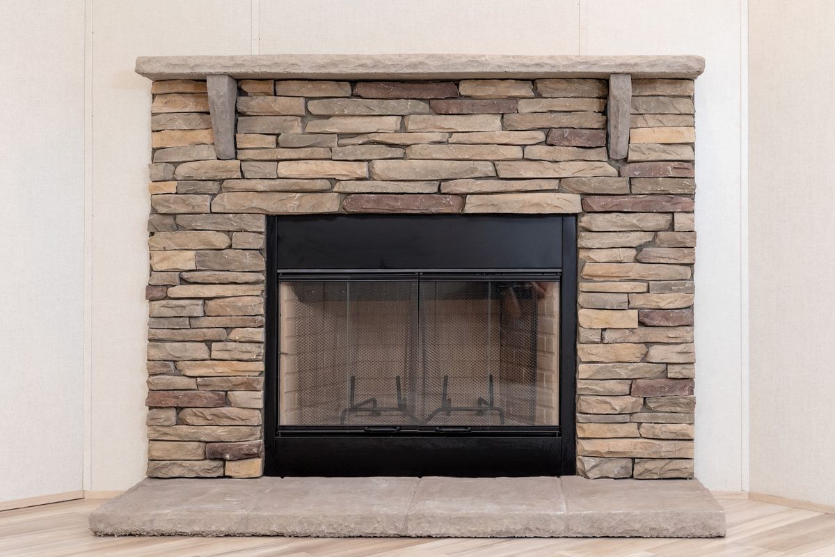 ec6c1cd8-2c00-4a7a-a88d-cbeda8d0f91d A stone fireplace in a room with wood floors.