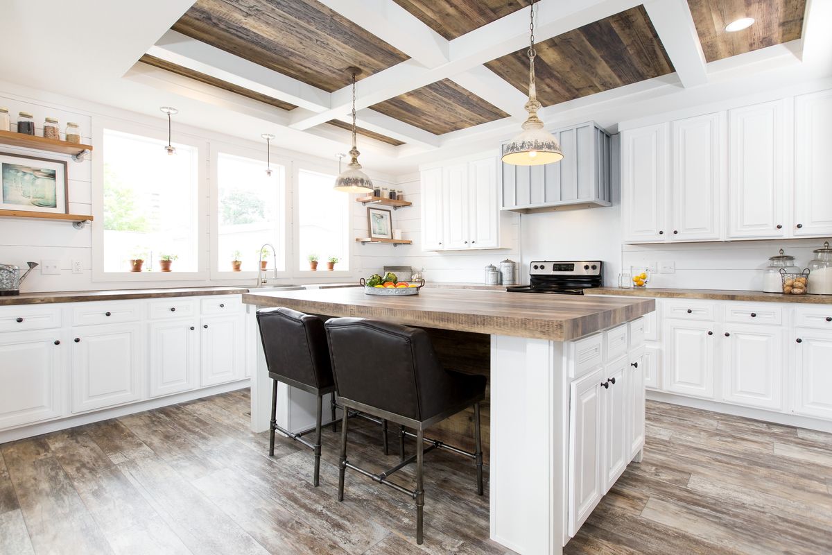A white kitchen with wood ceilings and a center island.