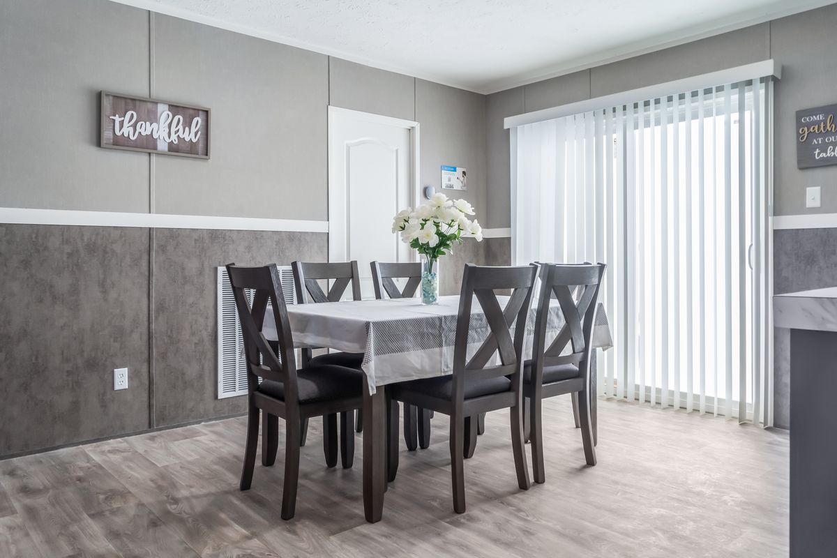 A dining room in a mobile home with gray walls.