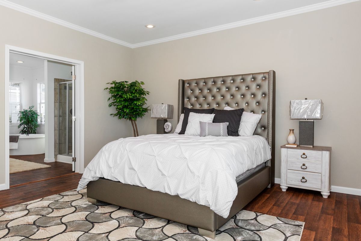 A bedroom with hardwood floors and a bed.