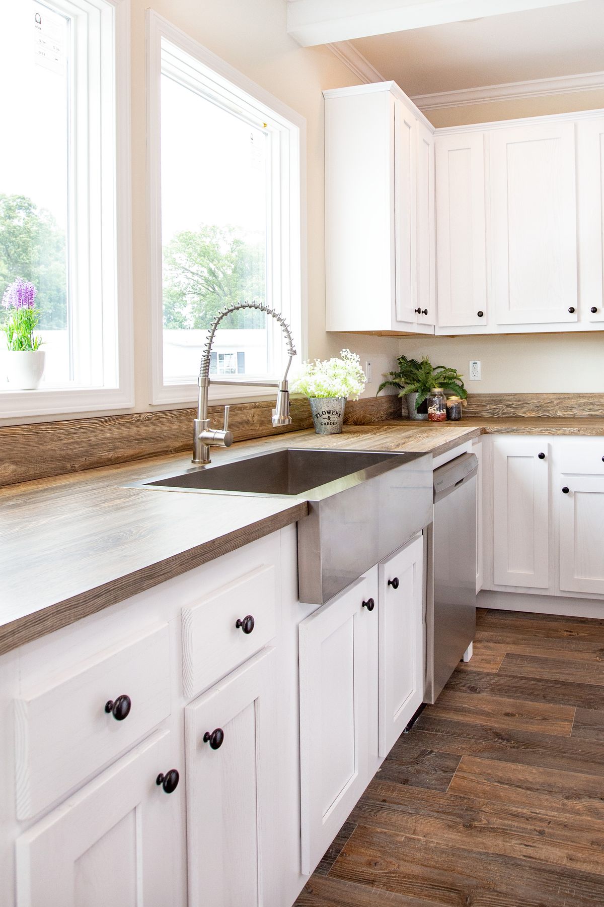 f97cc8b7-769c-40d7-bcbb-aaea6d3bc7d1 A kitchen with white cabinets and wood floors.